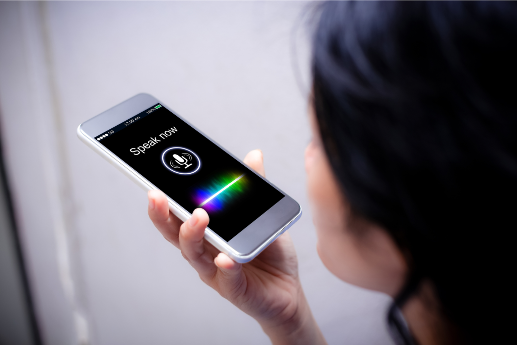 Woman using voice search optimization on her smartphone, speaking into the phone.