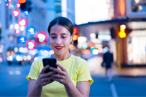 Woman smiling at smartphone with floating social media engagement icons showing likes and comments representing social media algorithms prioritizing content